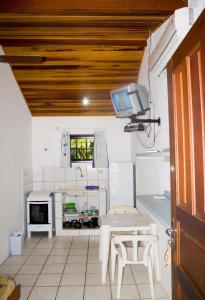 a kitchen with a table and a tv on the ceiling at Chalés Mariah in Ubatuba +41 photos