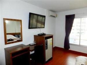 a living room with a tv on the wall and a mirror at Orchid Inn in Bangkok