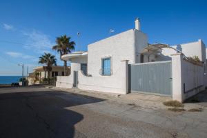 a white house with a fence and the ocean at Villetta Rossella Mancaversa in Marina di Mancaversa
