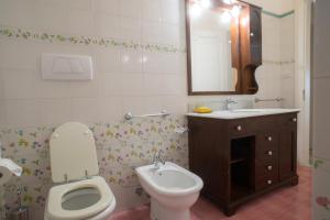 a bathroom with a toilet and a sink and a mirror at Villetta Rossella Mancaversa in Marina di Mancaversa +11 photos