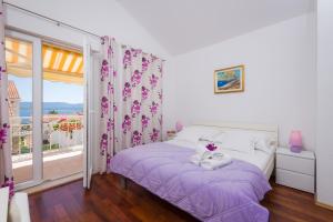 a bedroom with a bed with purple sheets and a window at Apartments Nada in Bol