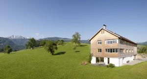 eine Luftansicht eines Hauses auf einem grünen Feld in der Unterkunft Schweizer Hof in Schwarzenberg im Bregenzerwald