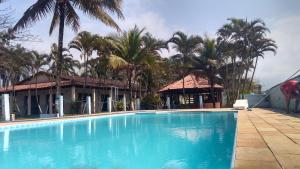 uma grande piscina em frente a um edifício com palmeiras em Pousada Jorai e Camping em Bertioga