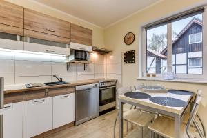 a kitchen with white cabinets and a table with chairs at Chëcz Kaszëbsko 59 in Załakowo
