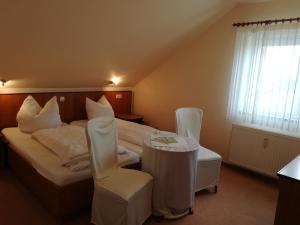 Habitación de hotel con 2 camas, mesa y sillas en Weinbau & Pension "8Zeilen" en Golk