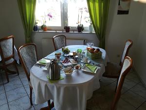 a table with a white table cloth and a tea kettle at Weinbau & Pension "8Zeilen" in Golk