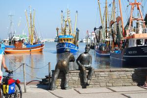 twoulptures of men sitting on a wall near a harbor at Hotel Peters in Neuharlingersiel