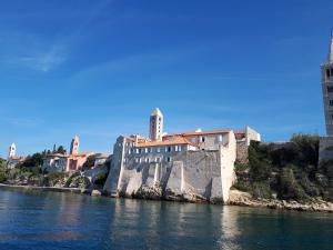 a building sitting on the side of a body of water at Apartmani Lucia in Rab