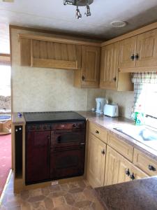 a kitchen with wooden cabinets and a stove top oven at 35 Glenfinart Park in Dunoon +4 photos