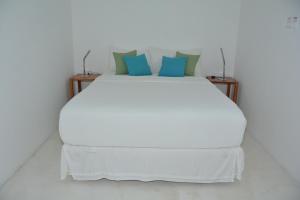 a white bed with blue pillows on top of it at Pattoo Castle in Negril