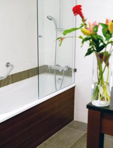 a bathroom with a glass shower with a vase of flowers at New Hotel Charlemagne in Brussels
