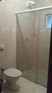baño con ducha, aseo y puerta de cristal en Apartamento para locação - cód 34, en Bombinhas