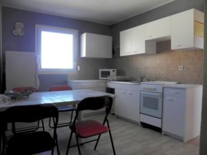 a kitchen with white cabinets and a table and chairs at les lavandes in Lablachère