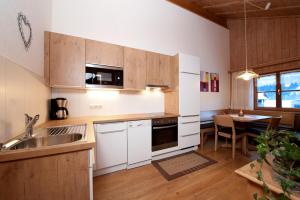 a kitchen with white cabinets and a table with a dining room at Kinderbauernhof in Schoppernau