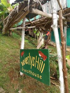 ein Schild für eine Pension mit Schild für eine Schmetterlingshütte in der Unterkunft Beverly's Hill Guest House in Bocas del Toro