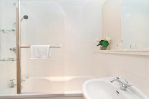 baño blanco con ducha y lavamanos en Edinburgh Church Apartments, en Edimburgo