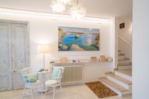 Hostal Marina Cadaqués في كاداكيس: غرفة معيشة مع طاولة وكراسي ولوحة