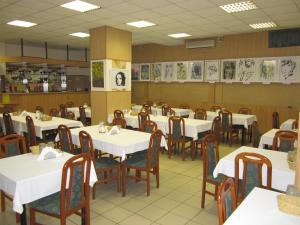 un comedor con mesas y sillas blancas en Apollo Motel, en Kecskemét