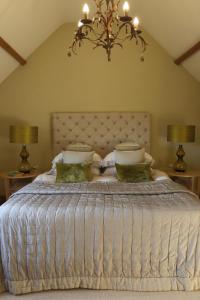 a bedroom with a white bed with two lamps and a chandelier at Oundle Bespoke Apartments in Oundle