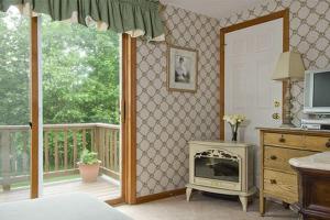 a bedroom with a fireplace in front of a balcony at Inn at Ellis River in Jackson