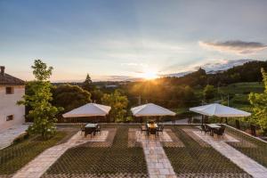 an outdoor patio with tables and umbrellas at sunset at Tenuta Sant'Eufemia in San Pietro di Feletto
