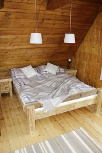 a bed in a wooden room with two pendant lights at Buflaczanka in Nowy Targ +21 photos