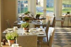 a dining room with tables and chairs and windows at The White House in Burnham Market