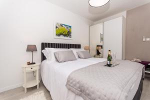 a white bedroom with a bed and a bottle of champagne at Adriatic Blue View in Split