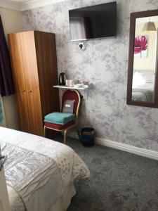 ein Schlafzimmer mit einem Bett, einem Spiegel und einem Stuhl in der Unterkunft The Tudor in Blackpool