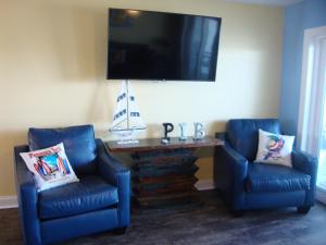 a living room with two blue chairs and a table with a tv at Put-in-Bay Waterfront Condo #210 in Put-in-Bay