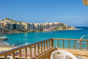 a balcony with a white chair and the ocean at Electra Guesthouse in Marsalforn