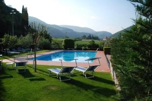 a swimming pool with chairs and mountains in the background at Hotel La Pergola in Grezzana