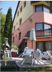 a building with chairs and an umbrella in front of it at Lillafüred Kapuja Hotel in Miskolc