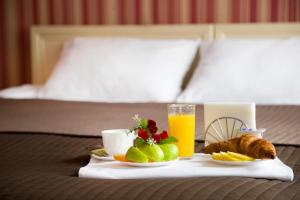 a tray of food and orange juice and fruit on a bed at Avenue in Saint Petersburg