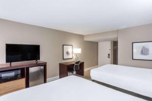 a hotel room with two beds and a flat screen tv at Stayable Gainesville in Gainesville
