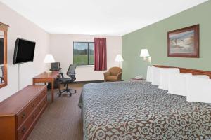 a hotel room with a bed and a desk and a television at Days Inn & Suites by Wyndham Brinkley in Brinkley