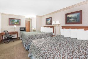 a hotel room with two beds and a desk at Days Inn & Suites by Wyndham Brinkley in Brinkley