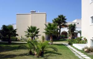 a large building with a large lawn and trees at Andromeda Hotel Apartments in Kos