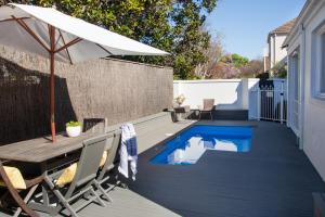 a patio with a table and an umbrella and a pool at Brighton House in Melbourne