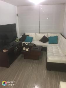Una sala de estar con un sofá blanco y un televisor. en Suite M&M, en Quito