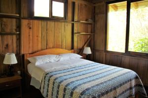 a bedroom with a bed with a blue and white blanket at Casitas de Madera in Mindo