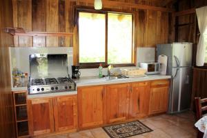 La cuisine est équipée d'armoires en bois, d'une cuisinière et d'un réfrigérateur. dans l'établissement Casitas de Madera, à Mindo