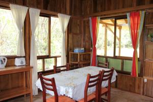 een kamer met een tafel, stoelen en ramen bij Casitas de Madera in Mindo