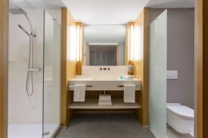 a bathroom with a sink and a toilet and a mirror at Chateau Royal Beach Resort & Spa, Noumea in Noumea