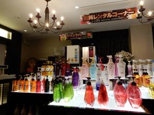 un comptoir avec de nombreuses bouteilles de différentes couleurs exposées dans l'établissement HOTEL VERSYS (Adult Only), à Hiroshima