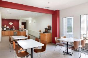 a dining room with two tables and a kitchen at Super 8 by Wyndham Garland Rowlett East Dallas Area in Garland