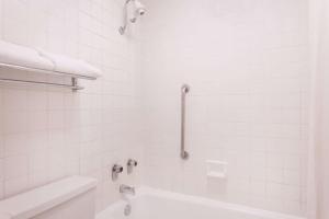 a white bathroom with a tub and a sink at Super 8 by Wyndham Macon West in Macon