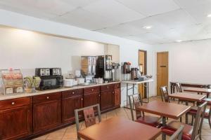 a kitchen with wooden cabinets and tables and chairs at Super 8 by Wyndham Pompano Beach in Pompano Beach