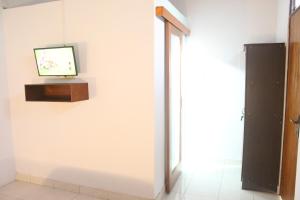 a room with a tv on a white wall at JS Guest House in Seminyak
