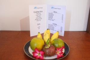 a plate of fruit on a table with a menu at JS Guest House in Seminyak